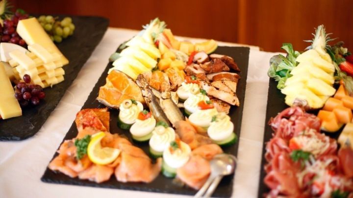 Ein Buffet mit vielf&auml;ltigen Speisen wird kunstvoll angerichtet, um G&auml;ste w&auml;hrend einer Feier zu bewirten.