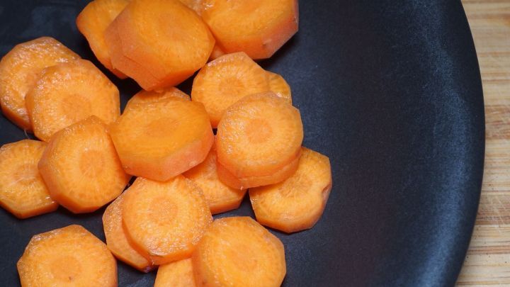 Auf einem schwarzen Teller liegen frisch geschnittene Karotten in verschiedenen Formen, bereit zum Essen durch Kinder.