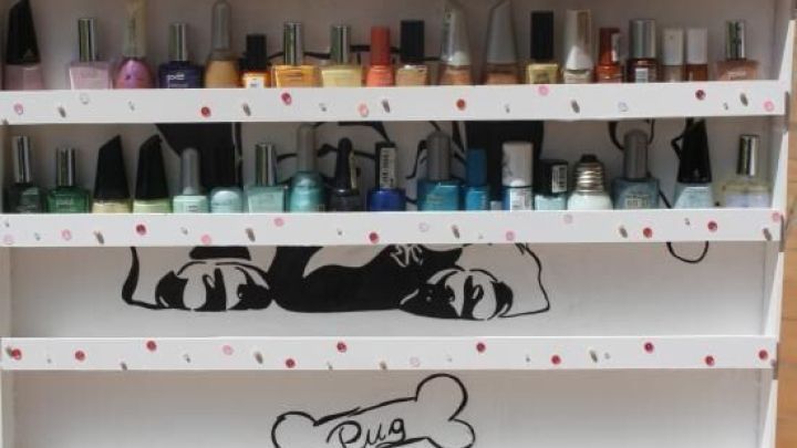 Nagellackregal zeigt bunte Nagellackflaschen, geordnet auf einem wei&szlig;en, gepunkteten DIY-Regal mit Hundezeichnung.