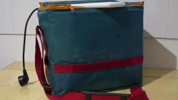 Eine K&uuml;hltasche mit angeschlossenem Stromkabel steht auf einem Tisch, bereit, eine elektrische Eismaschine zu betreiben.