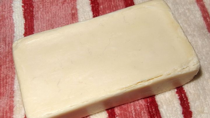 Ein St&uuml;ck Kernseife liegt auf einem gestreiften Tuch, bereit zur Verwendung f&uuml;r Hautpflege oder Haushaltsreinigung.