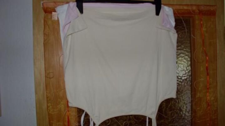 Ein &auml;rmelloses Shirt h&auml;ngt an einem Kleiderb&uuml;gel in einem Holzrahmen, bereit zur platzsparenden Aufbewahrung im Schrank.