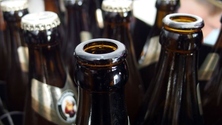Eine Bierflasche steht inmitten weiterer Flaschen, bereit, als Lebend-Mausefalle im Haushalt eingesetzt zu werden.