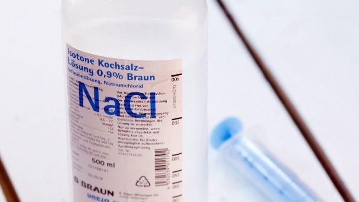 Eine Flasche mit Natriuml&ouml;sung steht neben einer Spritze, um Ohrenschmalzpfropfen bei Bedarf zu behandeln.