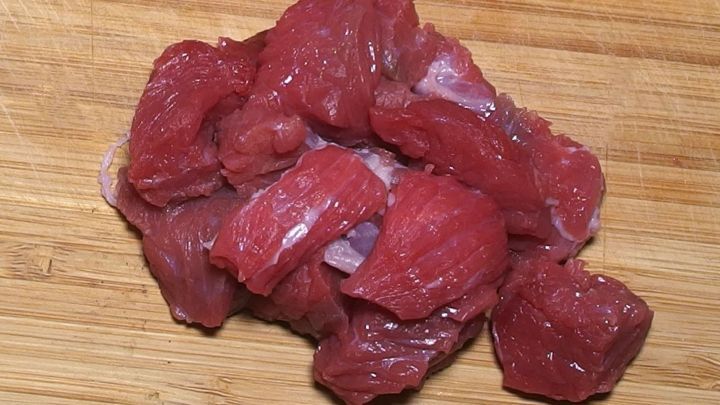 Fein geschnittenes Fleisch liegt auf einem Holzbrett, bereit f&uuml;r die Zubereitung von Chili con Carne.