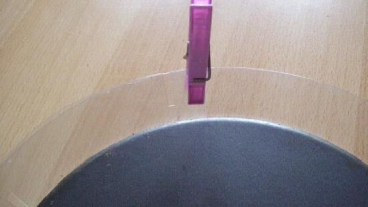 Ein transparenter Tortenring wird mit einer Klammer fixiert, w&auml;hrend er auf einem Holzuntergrund liegt.