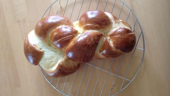 Ein Butterzopf liegt gl&auml;nzend auf einem Kuchengitter, frisch gebacken, bereit zum Servieren in einer heimischen K&uuml;che.