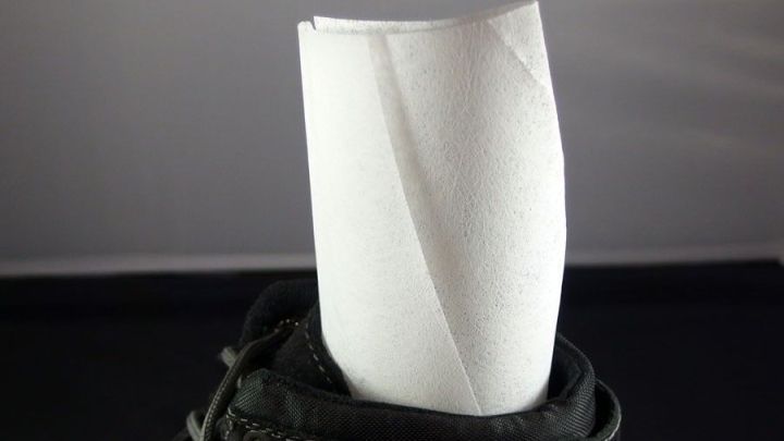 Ein Trocknertuch steckt in einem Schuh, um geruchsbildende Feuchtigkeit zu absorbieren und riechende Schuhe zu neutralisieren.