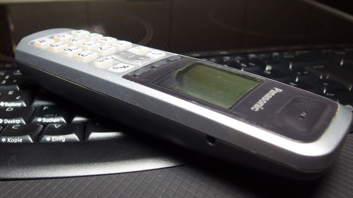 Eine kalte Tastatur dient als Unterlage f&uuml;r ein altes Telefon, w&auml;hrend es in einem schlichten Raum liegt.