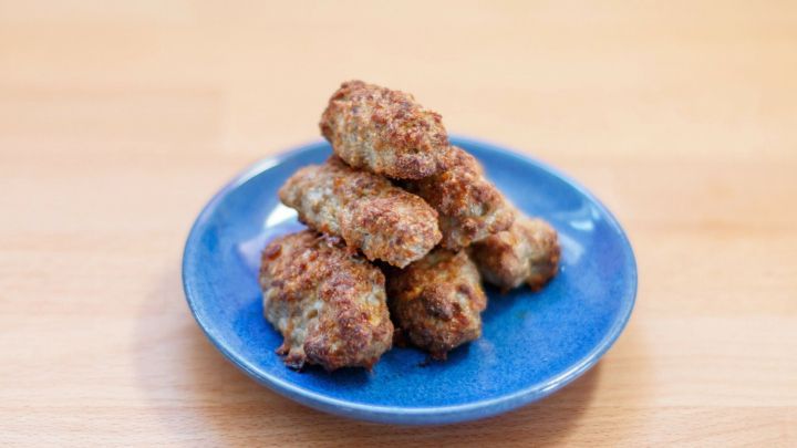 Auf einem blauen Teller liegen frisch gebackene Frikadellen, die appetitlich knusprig aussehen.