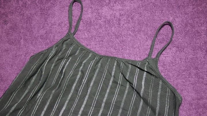 Ein gr&uuml;nes, gestreiftes Sportoberteil liegt auf einem lila Handtuch und wartet darauf, mit Handw&auml;sche gereinigt zu werden.