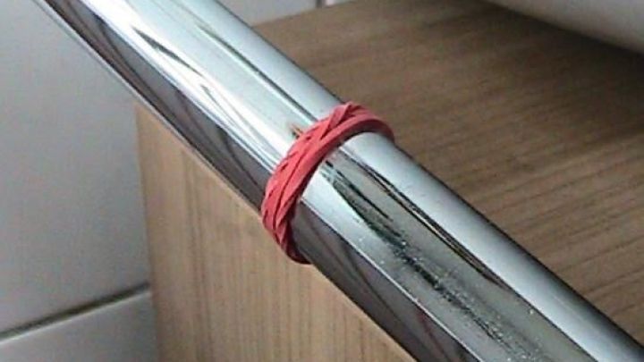 Ein Handtuchhalter aus Metall hat ein rotes Gummiband angebracht, um Handt&uuml;cher rutschfester im Badezimmer zu halten.