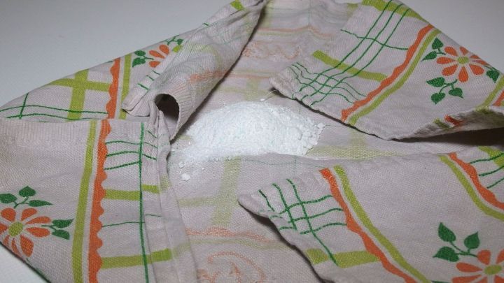 Ein verschmutztes Kleidungsst&uuml;ck liegt auf einer Oberfl&auml;che, w&auml;hrend Waschpulver direkt darauf gestreut wird.