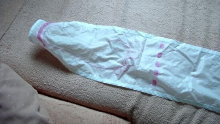 Ein Kompressionsstrumpf liegt gefaltet auf einem hellen Sofa und wartet darauf, leichter angezogen zu werden.