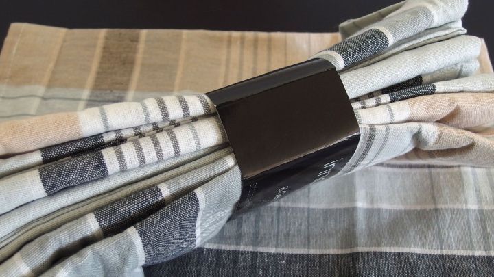 Gestreifte Geschirrhandt&uuml;cher liegen ordentlich zusammengewickelt auf einem dunklen Tisch, bereit zum Einsatz in der K&uuml;che.