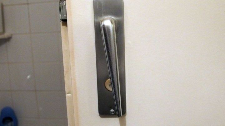 Ein T&uuml;rgriff aus Edelstahl an einer wei&szlig;en T&uuml;r, der anscheinend nicht mehr bet&auml;tigt werden kann.