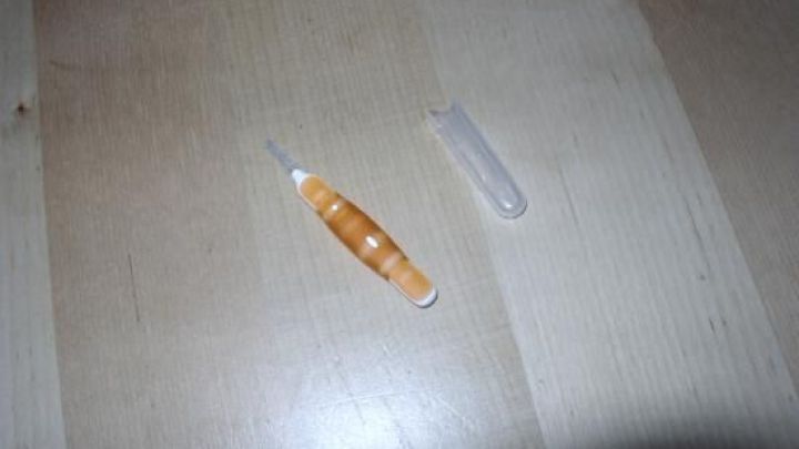 Zwei kleine Reinigungsger&auml;te liegen auf einem Holztisch. Eines ist orange, das andere ist transparent.