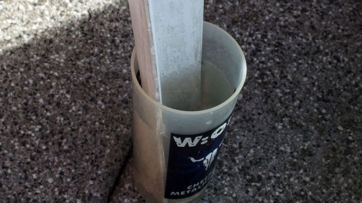 Ein Plastik Trinkbecher steht auf dem Boden und h&auml;lt einen Holzstab, um Ameisen beim Grillen abzuwehren.