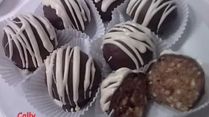 Sechs schokoladene Kugeln mit wei&szlig;em Zuckerguss in einer Kreation pr&auml;sente auf einem wei&szlig;en Teller, einige sind aufgeschnitten.