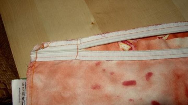 Ein Kopfkissenbezug mit einer ungew&ouml;hnlichen, fleckigen Textur liegt auf einem hellen Holztisch, teilweise ge&ouml;ffnet.