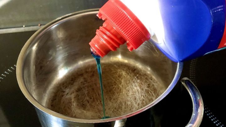 Ein Topf wird mit Toilettenreiniger gef&uuml;llt, um angebrannte R&uuml;ckst&auml;nde in einer modernen K&uuml;che zu entfernen.