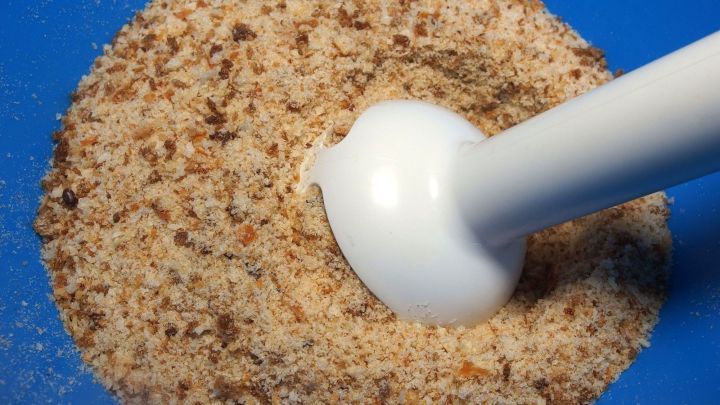 Feine Semmelbr&ouml;sel werden durch einen P&uuml;rierstab in einer blauen Sch&uuml;ssel zubereitet, um eine gleichm&auml;&szlig;ige Konsistenz zu erzielen.