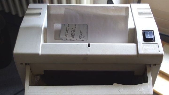 Ein Aktenvernichter zerkleinert gerade eine Dokumentenseite in einem B&uuml;ro, um Belege einfach zu vernichten.