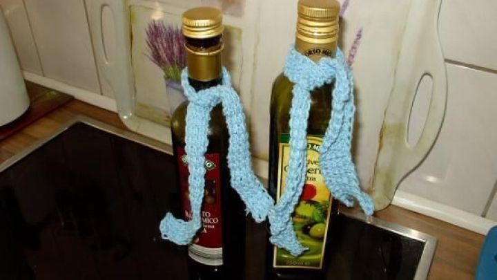 Zwei &Ouml;lflaschen stehen auf einer K&uuml;chentheke, jede mit einem blauen, gestrickten Bezug, um Tropfen zu verhindern.
