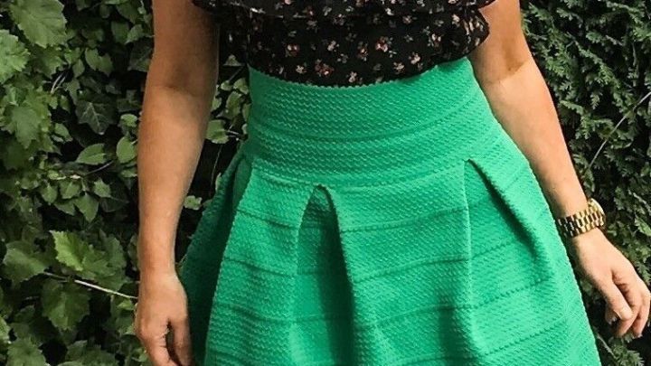 Ein schicker, elektrostatisch aufgeladener Rock in kr&auml;ftigem Gr&uuml;n wird bei sonnigem Wetter getragen, umgeben von gr&uuml;nen Pflanzen.