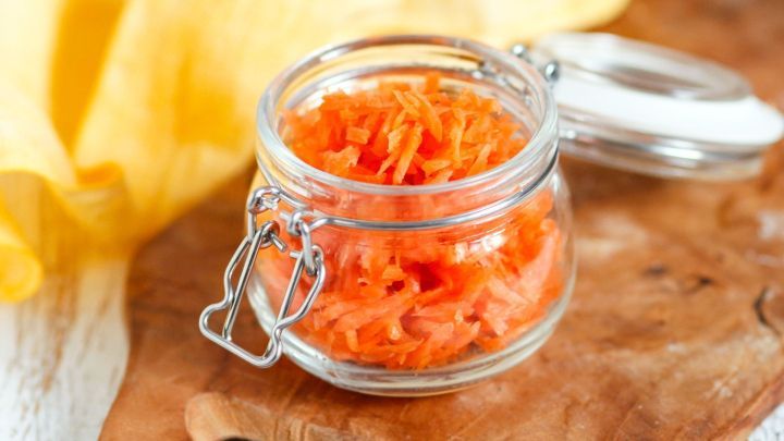 Ein Glas mit M&ouml;hrensalat steht auf einem Holzbrett, umgeben von gelben Stoffservietten in einer hellen Umgebung.