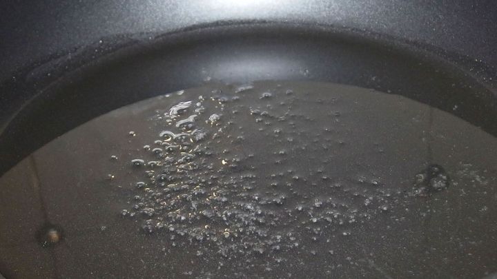 Eine gl&auml;nzende Pfanne mit hei&szlig;em &Ouml;l, in dem Fett spritzt, w&auml;hrend das Braten von Lebensmitteln beginnt.