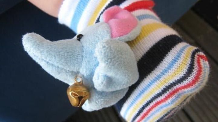 Bunte Babysocke mit einem kleinen Elefanten und Gl&ouml;ckchen, w&auml;hrend das Kind fr&ouml;hlich strampelt.
