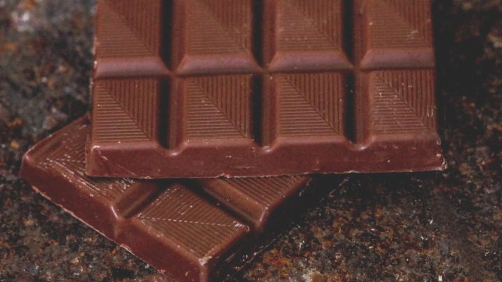 Dunkle Schokolade liegt auf einer rustikalen Oberfl&auml;che, was die Verbindung zu Akne und Ern&auml;hrung verdeutlicht.