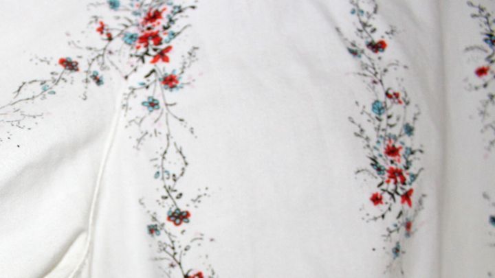 Ein wei&szlig;es, blumig verziertes Textilst&uuml;ck liegt, ideal f&uuml;r die Behandlung von Bierflecken mit Brennspiritus.