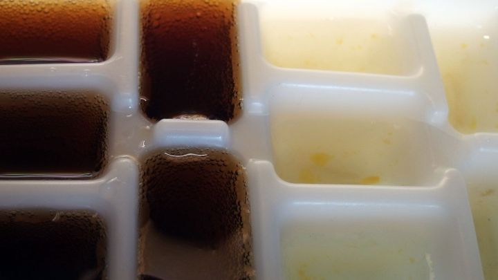 Eisw&uuml;rfel in einer K&uuml;hlschrankform, gefroren mit verschiedenen Fl&uuml;ssigkeiten, stehen bereit zur Verwendung in Getr&auml;nken.