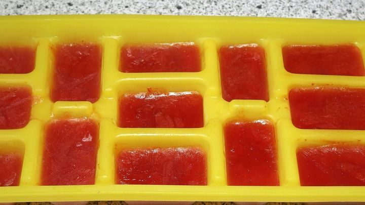Kalter Tomatensaft in einem gelben Eisw&uuml;rfelform, eingefroren und bereit zur Verwendung in Getr&auml;nken oder Gerichten.