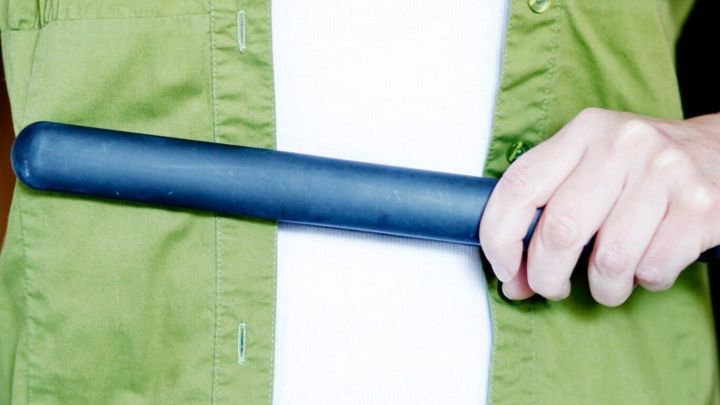 Ein Gl&auml;tteisen wird von einer Hand gehalten, bereit zum Einsatz auf einem Kleidungsst&uuml;ck in einem h&auml;uslichen Umfeld.