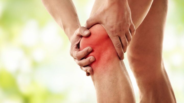 Eine Person h&auml;lt sich schmerzhaft das Knie, w&auml;hrend sie in einer gr&uuml;nen, nat&uuml;rlichen Umgebung steht. Arthrose kann helfen.