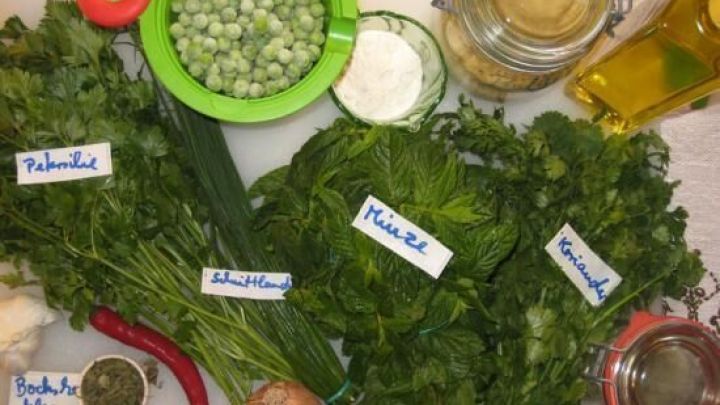 Frische Kr&auml;uter und Erbsen liegen auf einem Tisch, bereit zur Zubereitung von vegetarischen Erbsenb&auml;llchen.