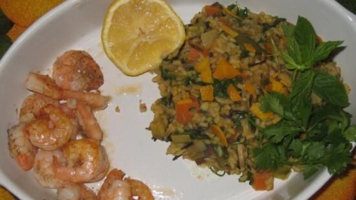 K&ouml;stlicher Juwelenreis und Garnelen sind appetitlich angerichtet, umgeben von frischen Kr&auml;utern und einer Zitrone.