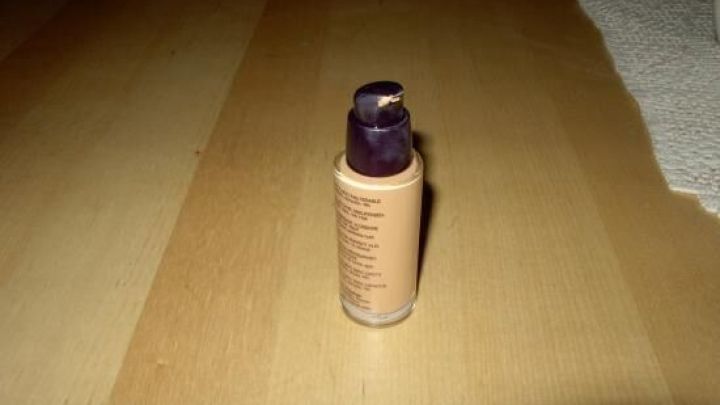 Ein Fl&auml;schchen mit Make-up steht auf einem Holztisch, bereit, Pickel unsichtbar zu machen und das Gesicht abzudecken.