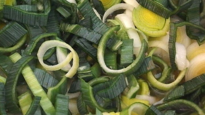 Frisch geschnittene Lauchstreifen liegen &uuml;bereinander und wirken saftig, bereit zum Kochen oder W&uuml;rzen in einer bunten Gem&uuml;sepfanne.