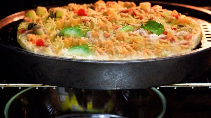 Ein Backblech mit einer warmen Pizza wird im Ofen erw&auml;rmt, um Energie zu sparen, w&auml;hrend eine Glassch&uuml;ssel darunter steht.