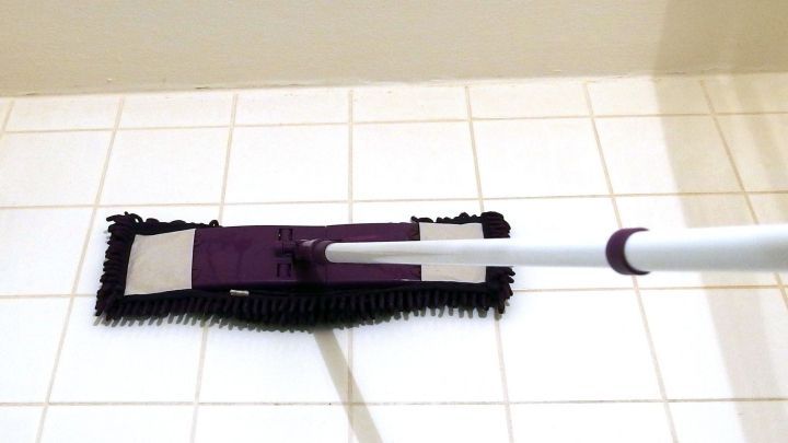 Ein Bodenwischer reinigt graue Wandfliesen, indem er sanft &uuml;ber die Keramiken gleitet, in einem hellen Raum.