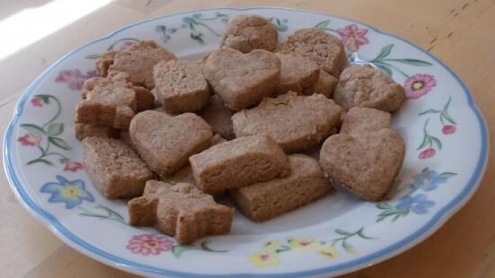 Auf einem Teller liegen verschiedene St&uuml;cke Buttergeb&auml;ck in Herzen und Rechtecken, umgeben von einem floral verzierten Rand.