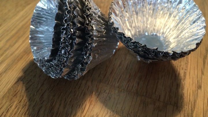 Zwei kleine, silberne Kerzenst&auml;nder aus Aluminium stehen auf einem Holzuntergrund und wirken ungenutzt.