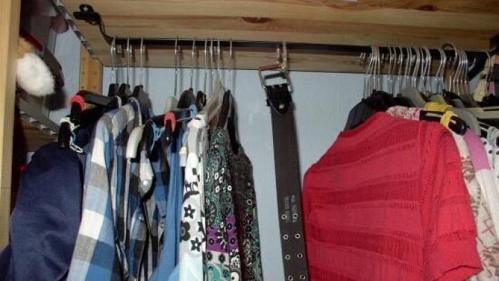 Ein G&uuml;rtel h&auml;ngt ordentlich zwischen mehreren Hemden in einem Kleiderschrank, der den Raum effizient nutzt.