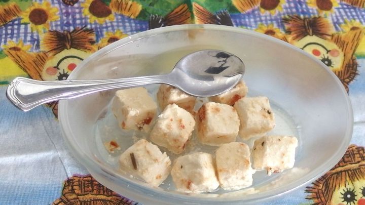 Ein L&ouml;ffel liegt in einer Sch&uuml;ssel mit kleinen W&uuml;rfeln, umgeben von einem bunten Tischdeckenmuster.