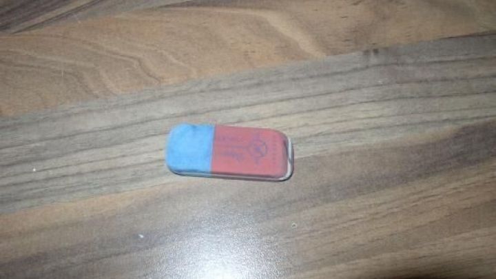 Ein Radiergummi liegt auf einem Tisch, bereit zum Reinigen, auf der Holzoberfl&auml;che sichtbar und unbenutzt.