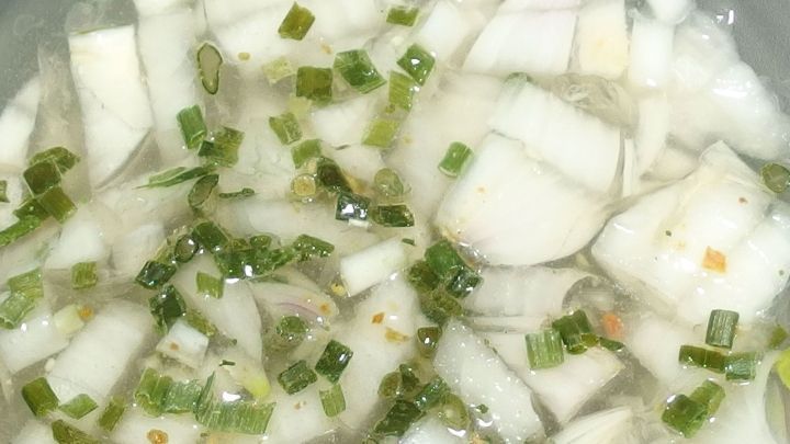 In einer Sch&uuml;ssel liegen gehackte rohe Zwiebeln und gr&uuml;ne Zwiebelringe in einer klaren Fl&uuml;ssigkeit, bereit zum Servieren.